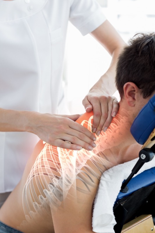 A therapist providing pain relief by massaging the patient's shoulder.