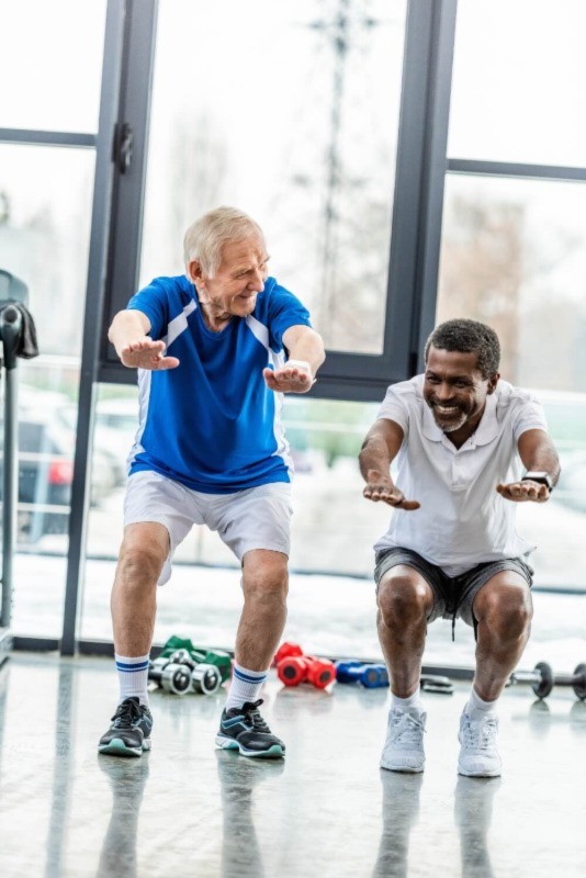 Two men joyfully performing squat exercises.